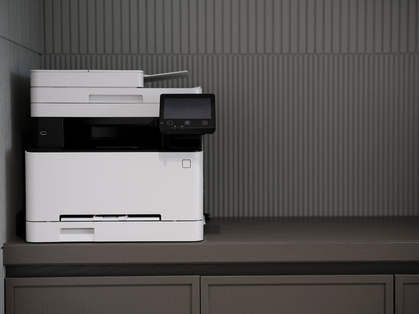 Multifonction A4 de bureau posé sur une crédence, dans un bureau en lumière basse