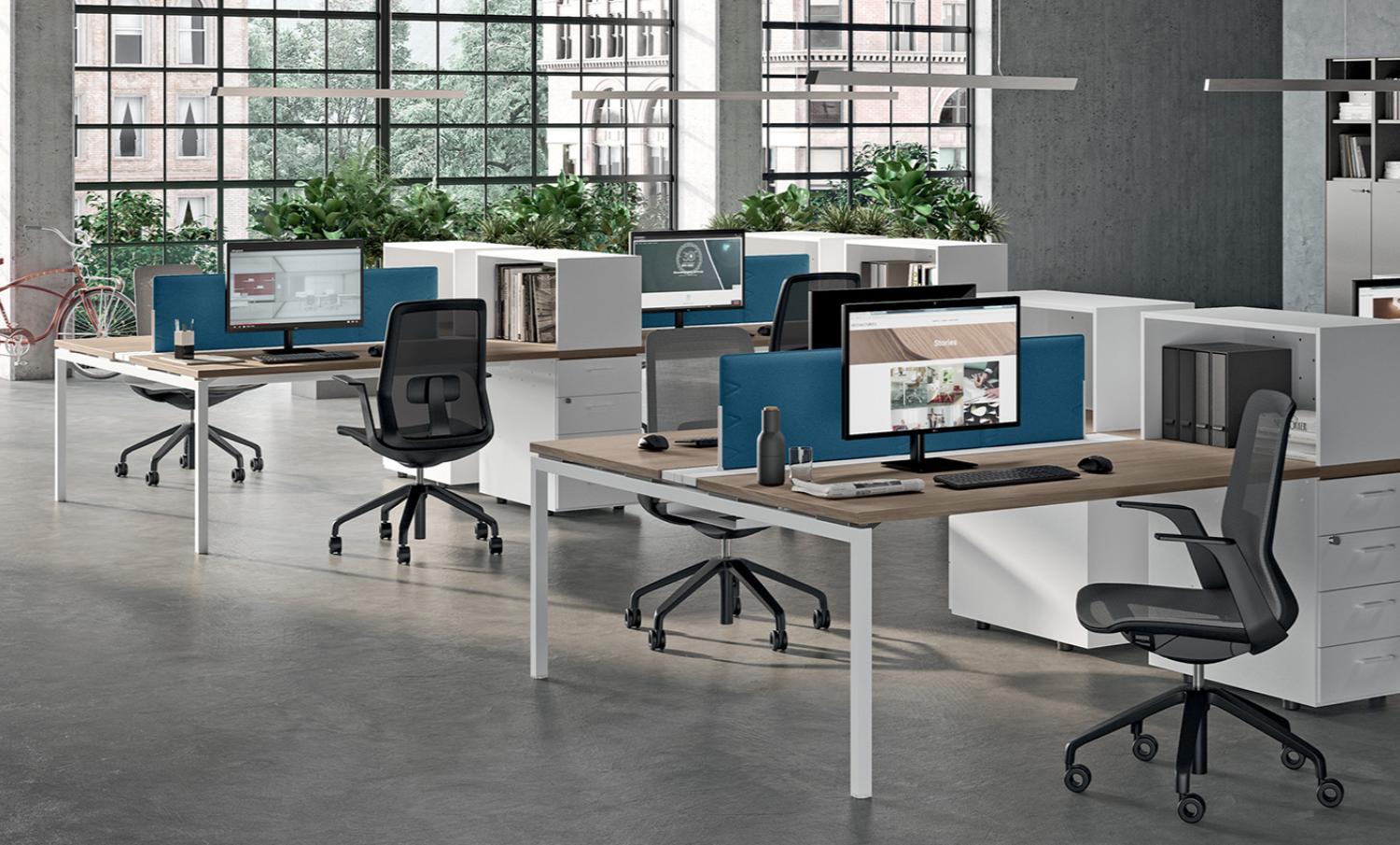 Postes en bench Quadrifoglio&nbsp;: écrans de séparation bleus, sièges ergonomiques en résille et rangements blancs — visuel fabricant.