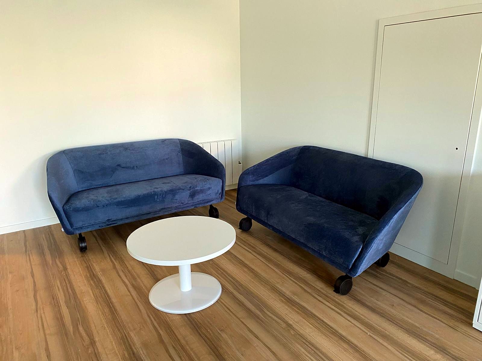 Espace détente : deux canapés velours bleu nuit et table basse ronde