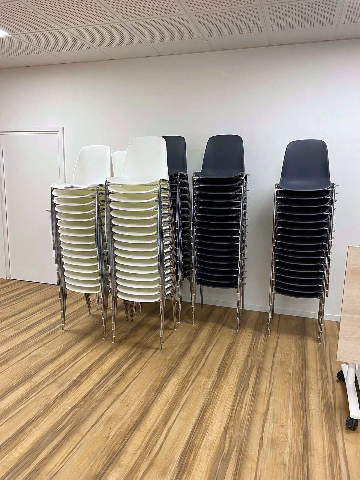 Chaises coque blanches et noires livrées en piles